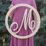 Woman holding wooden monogram circle script letter sign