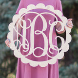 An image of a woman holding a pink painted scallop style wooden monogram sign from 48 Hour Monogram.