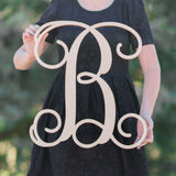 An image of a woman holding a wooden monogram sign in regular font from 48 Hour Monogram.