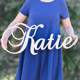 Woman holding wooden name sign in curly font