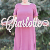 Woman holding wooden name sign in curly font