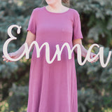 Woman holding wooden name sign in curly font