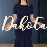 Woman holding wooden name sign in curly font