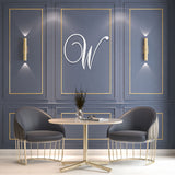white one letter monogram on living room wall above chairs