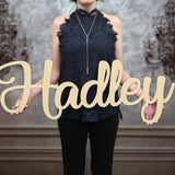 Woman holding wooden name sign in curly font