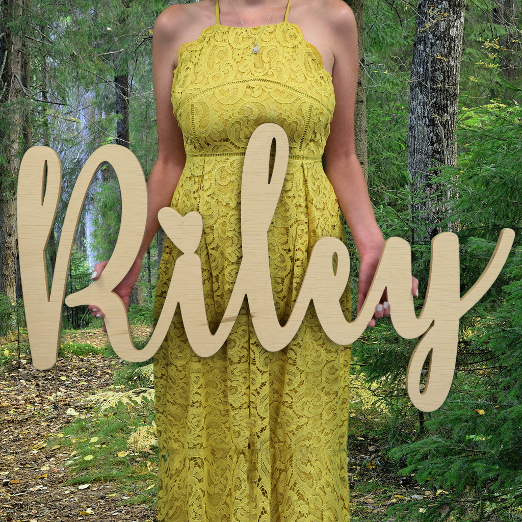 Woman holding wooden name sign in curly font