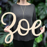 An image of a woman holding a wooden monogram sign from 48 Hour Monogram in the Zoe font.